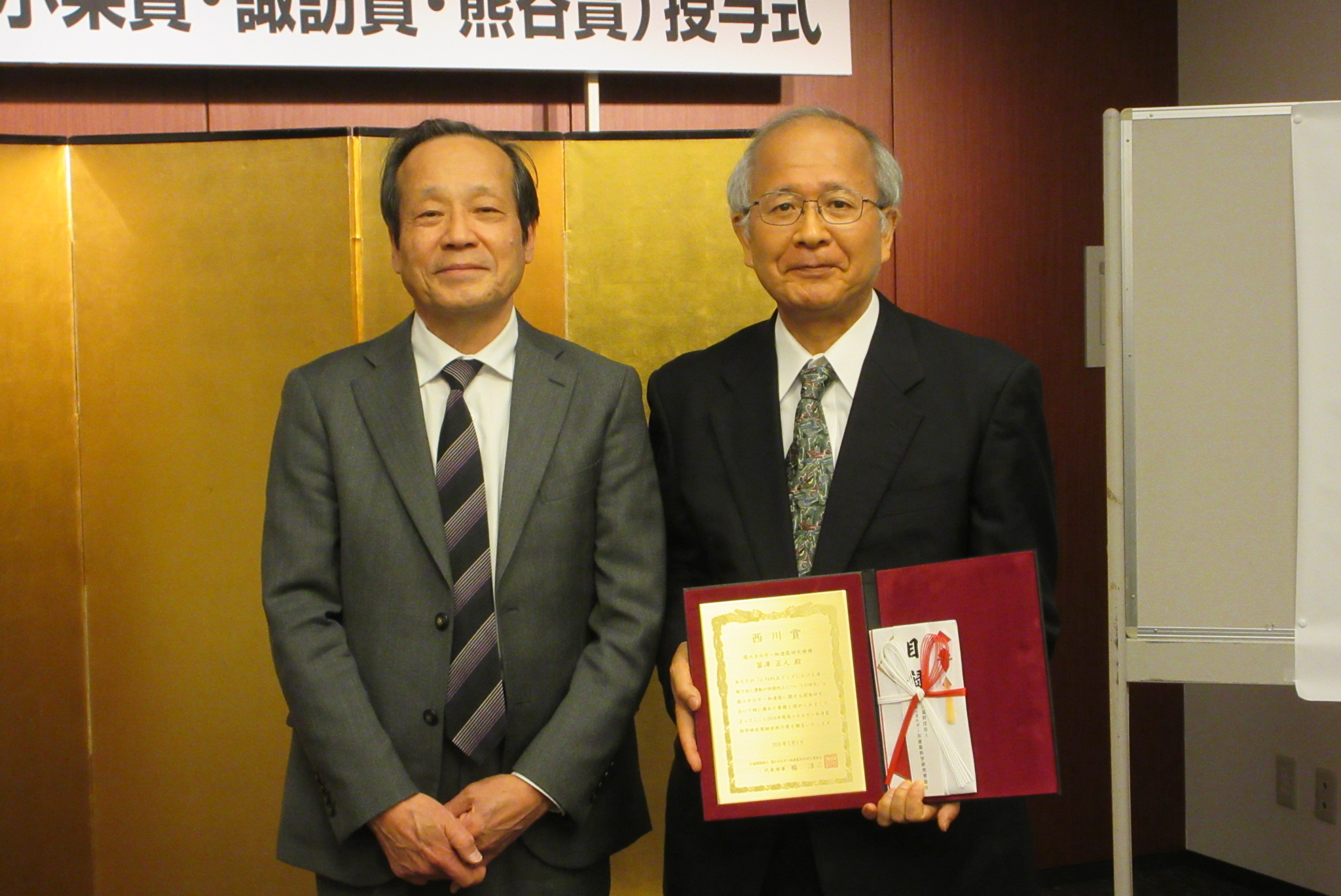 左から高エネルギー加速器奨励会代表理事の幅 淳二(はば・じゅんじ)氏と受賞した冨澤 正人(とみざわ・まさひと)氏
